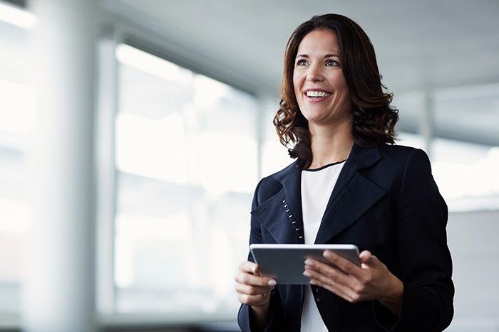 A happy woman in black suit holding an ipad