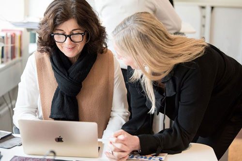Två kollegor som diskuterar framför en laptop