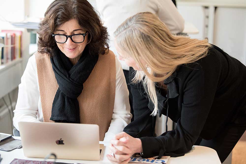 Helena Korduner från Amazing Leaders samtalar med en kollega vid en dator om framtidens ledarskap och AI.